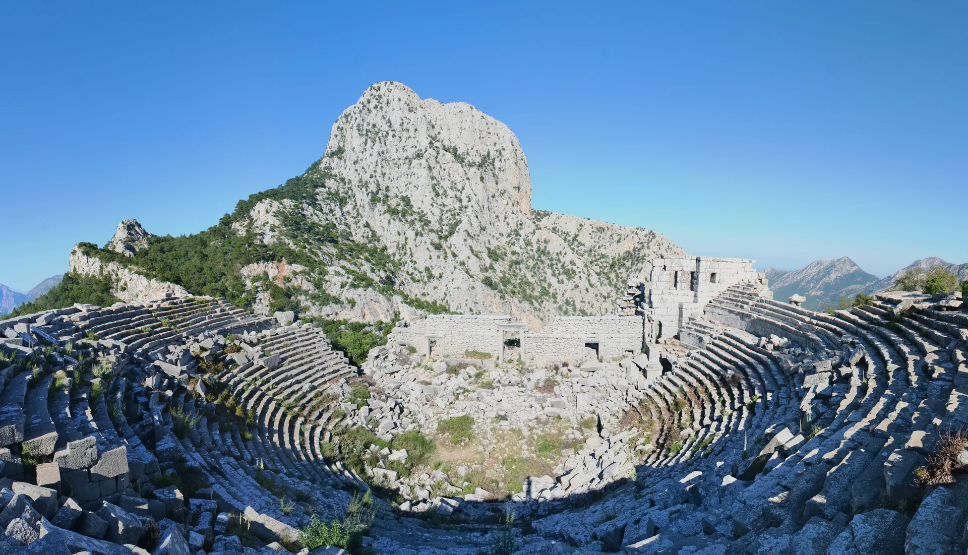Termessos antik tiyatrosu ve arkasında yükselen Güllük Dağı zirveleri